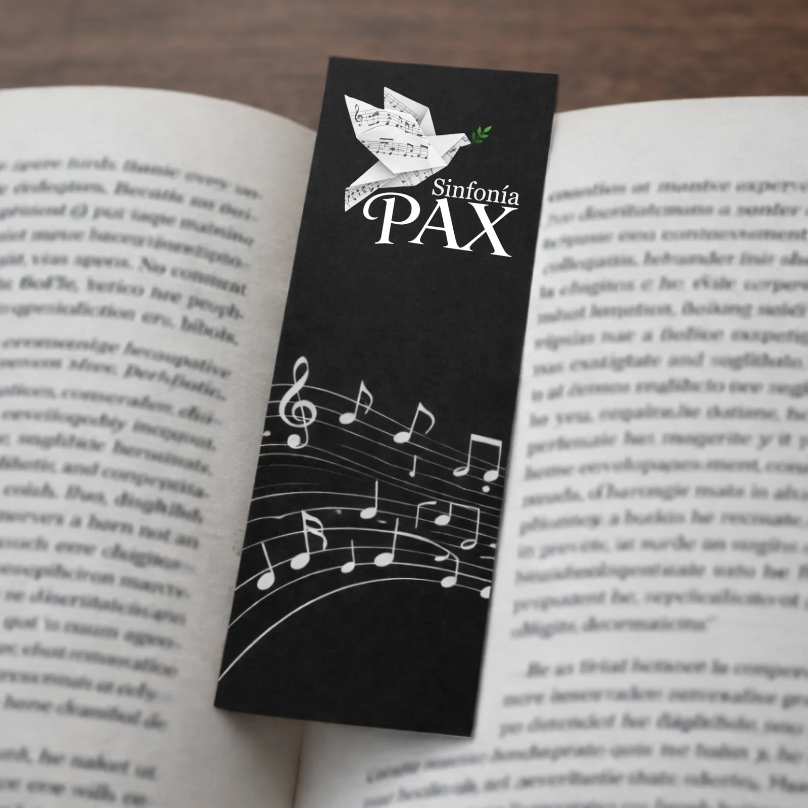 Marcapáginas negro de Sinfonía PAX sobre un libro abierto